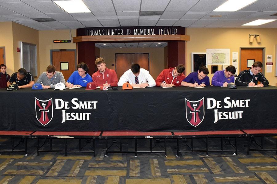 Nine athletes sign their athletic letters of intent in the Emerson lobby. From left: Leonard Jones to Lindenwood for lacrosse, Justin Evers to Southwest Illinois College for baseball, Matthew Wahle to Rockhurst for golf, Erik Miller to Stanford for baseball, Griffin Palmer to Illinois for football, Drew Nuelle to Indiana for soccer, Matt Yankowitz to Truman State for soccer, Jack Klingel to Northern Iowa for golf, and Kyle Bennett to Benedictine Illinois for football.