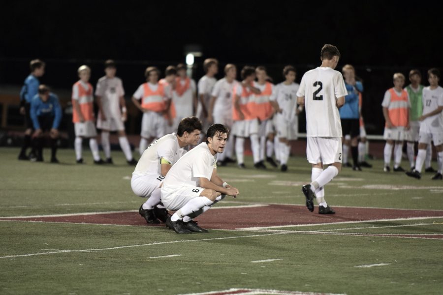 Senior David Meyerhoff and Jack Klingler squat at mid-field after losing to their home opening game against Marquette in shootouts.