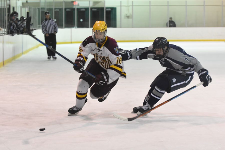 Senior defenseman Michael Arens fights for the puck during the teams last match-up with SLUH,