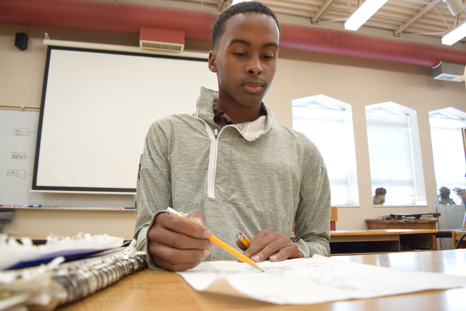 Using pencil, Senior Darian Sandoz works on his 100 Neediest Cases project. This is Sandoz's third year working on the project.
