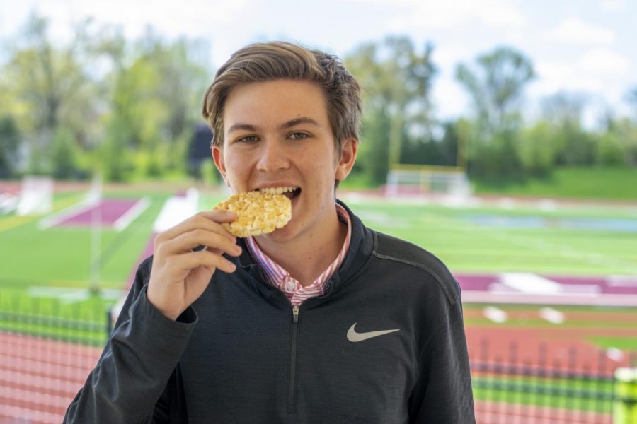 Senior Luke Bunkers bites a rice cake like an it’s an Olympic gold medal outside the Ballas entrance.