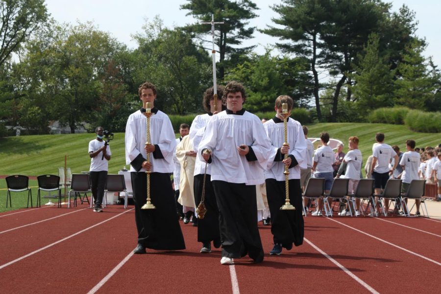 Altar servers Tommy Hashbarger, Aiden Madigan, Daniel Dowell, and Jack Stanley lead the clergy out of the stadium to end the Mass of the Holy Spirit.