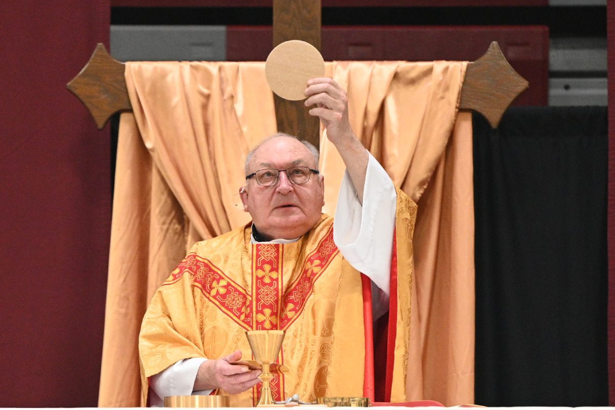 Fr. Jim Burshek S.J. consecrates the host during the Eucharist at the All Saints Mass on Nov. 1. 