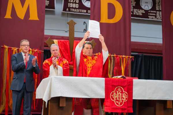 School President Ronny O'Dwyer S.J. shows the signed sponsorship agreement to the audience during the Mass of the Holy Spirit Sept. 6.