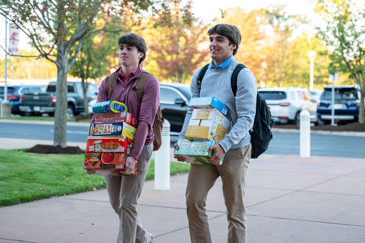 Michael Scally '25 and Michael Schmidt '25 carry cans of food into Emerson lobby as part of the Great Ignatian food drive on Oct. 17.