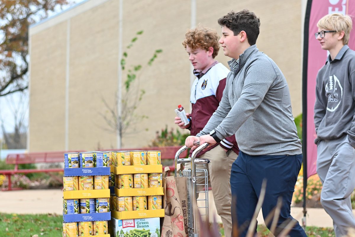 Tony Zola '27, Luca Gruzska '27, and David Cunningham '28 bringing out cans during the Great Ignatian Challenge. 