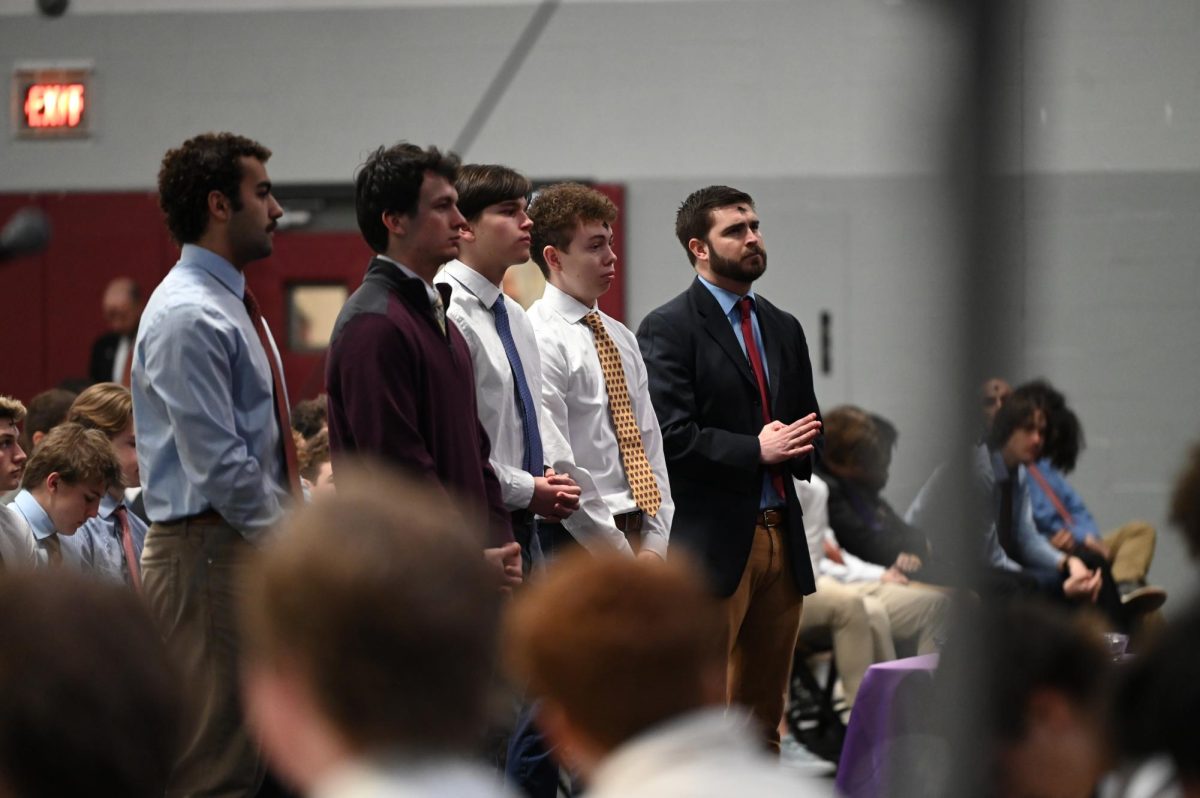 Henry Barreca ‘25, Will Harbaugh ‘25, Ari Cox ‘26, Joe O’Connell ‘28, and Andrew Shipp ‘07 stand in front of the altar during the all school Ash Wednesday mass to be recognized for their journey to receiving sacraments.