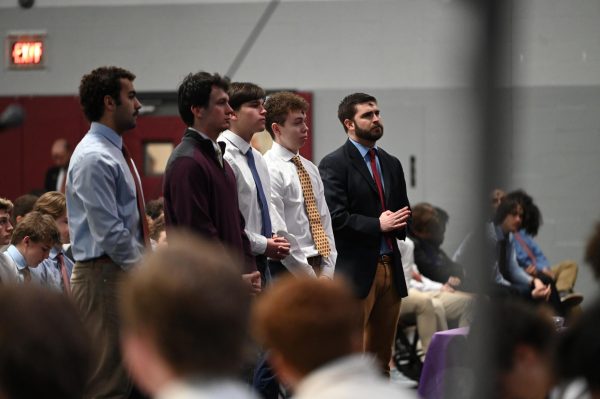 Henry Barreca ‘25, Will Harbaugh ‘25, Ari Cox ‘26, Joe O’Connell ‘28, and Andrew Shipp ‘07 stand in front of the altar during the all school Ash Wednesday mass to be recognized for their journey to receiving sacraments.