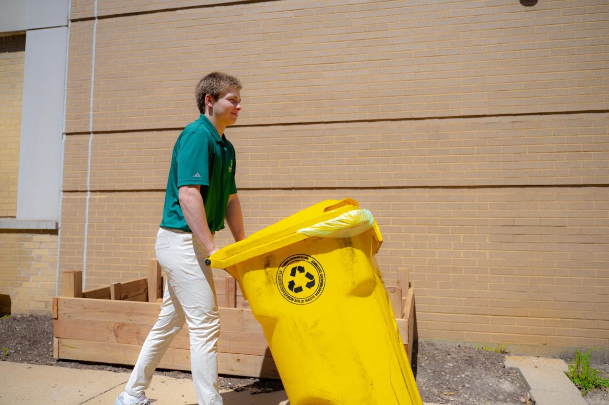 Green team president Billy Walbert rolling the composting bins outside.