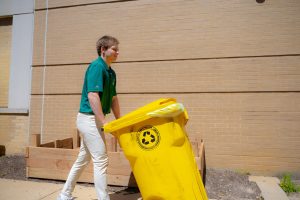 Green team president Billy Walbert rolling the composting bins outside.
