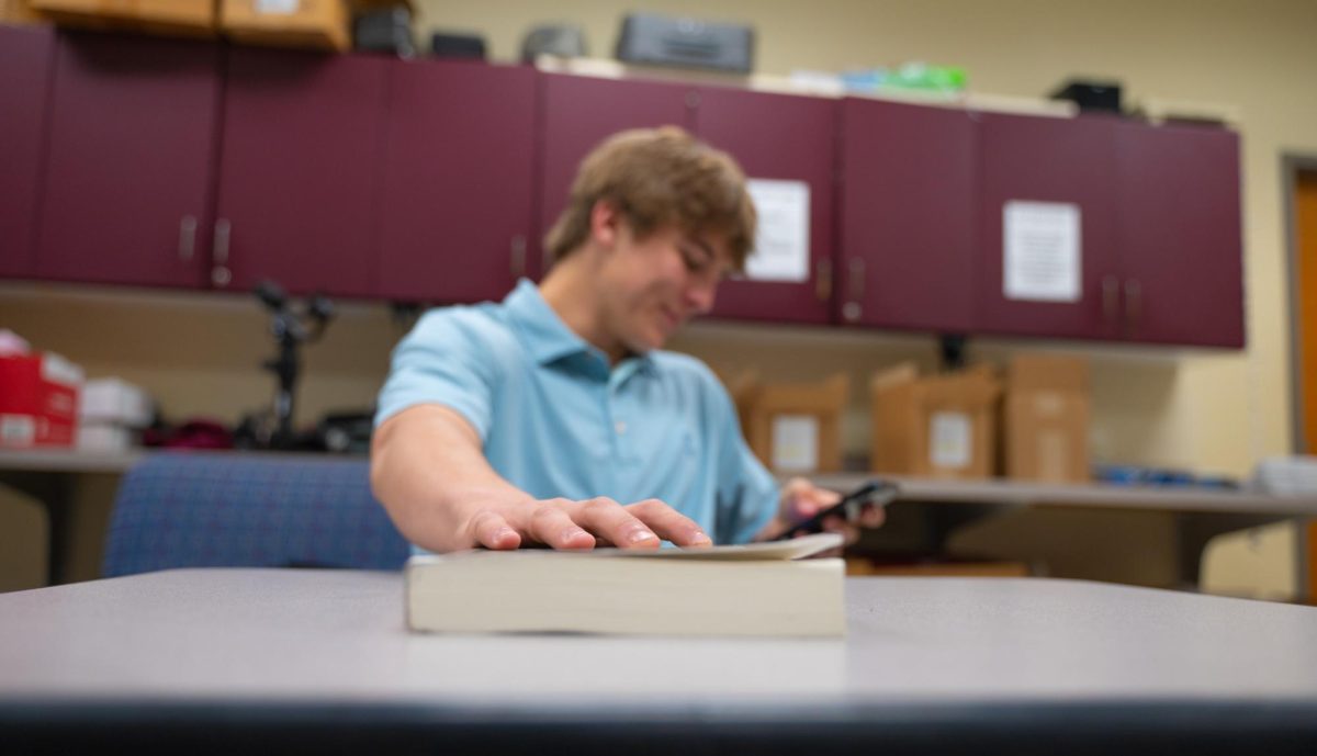 Tommy Basara 26' pushes away a book as he scrolls on his phone. As technology progresses, reading amongst teens is slowly fading away, and not for the better.