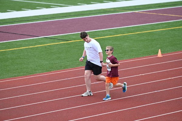 Luca Gruska '27 runs with athlete during 50 meter race for Special Olympics on May 7th, 2025.