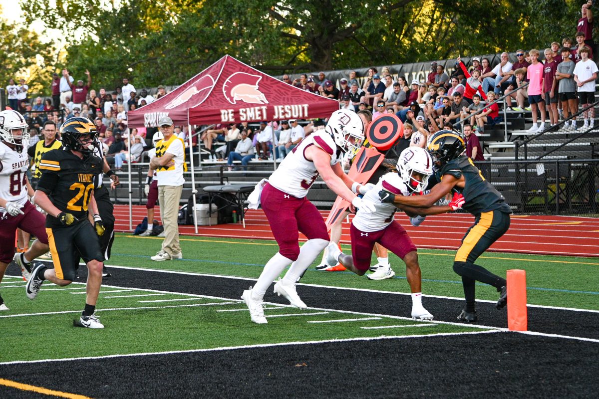 A Spartan runner powers through a defender at the edge of the end zone to score.
