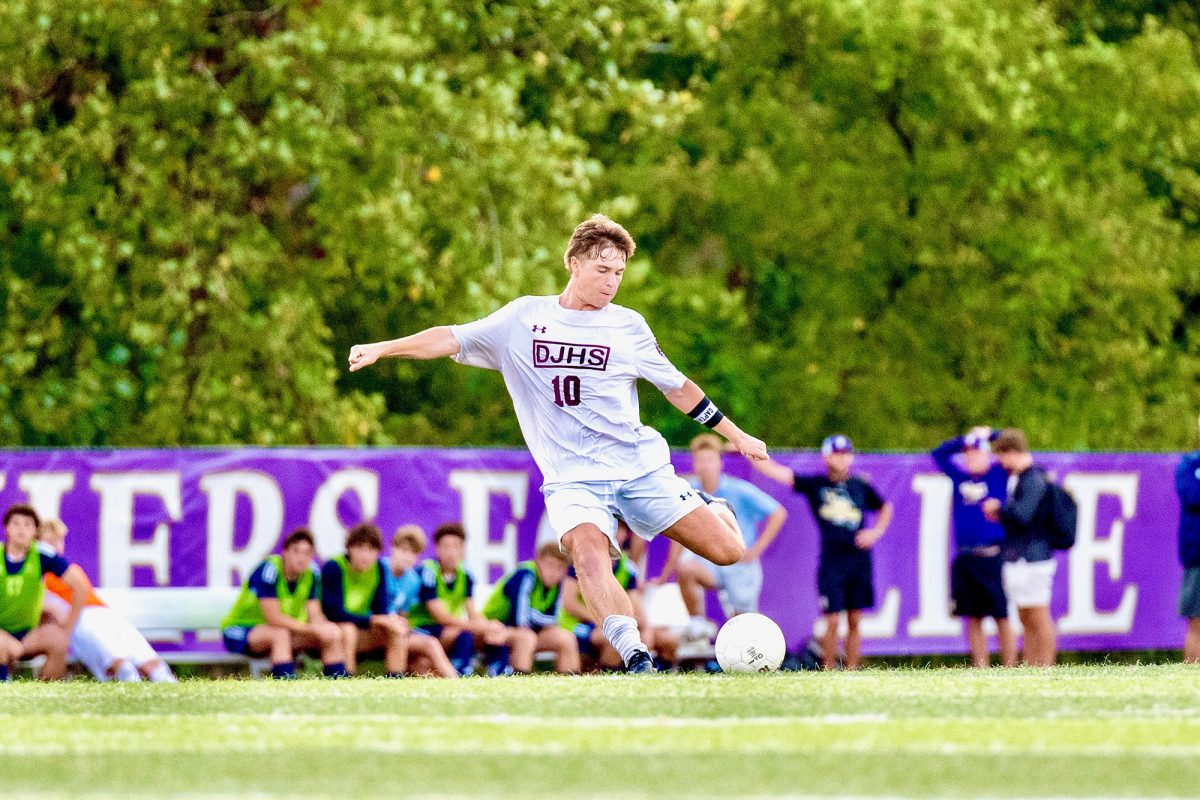 Soccer player kicks ball downfield in Varsity Soccer game vs SLUH. Photo taken by James Hadican ‘29.