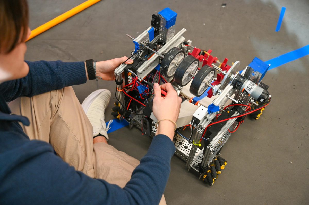 Evan Herring '26 repairs and reconnects a new control hub last minute to resolve the robot's malfunction.