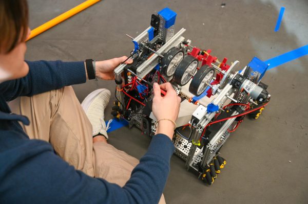 Evan Herring '26 repairs and reconnects a new control hub last minute to resolve the robot's malfunction.